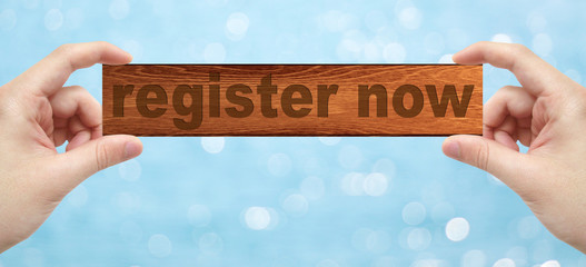 Hands holding a wood engrave with word register now