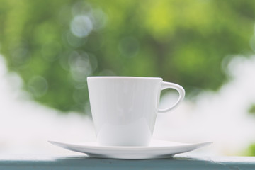 White coffee cup with outdoor view background - vintage filter e