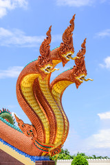 Three heads dragon statue on staircase in temple with blue sky.