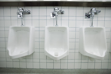 Three white urinals in men's bathroom