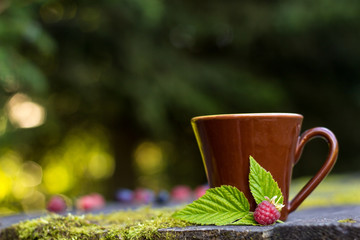 ceramics cup with raspberries on knitted on a wooden table. Shooting in the outdoor.