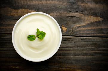 Close up of homemade yogurt in the bowl on wooden background