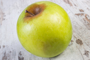 Spoiled apple on old wooden white table