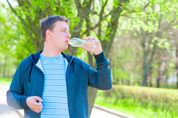 Fototapeta premium man in a sports suit drinking water from a bottle
