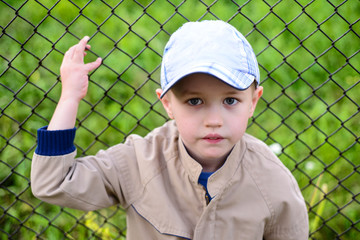 Portrait of a little boy on the background of the fence
