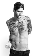 Fototapeta premium Sexy tattooed man portrait looking at camera black and white