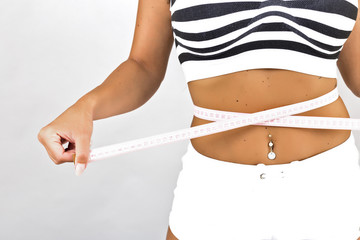 Closeup of  young woman measuring  her waist with a measure tape