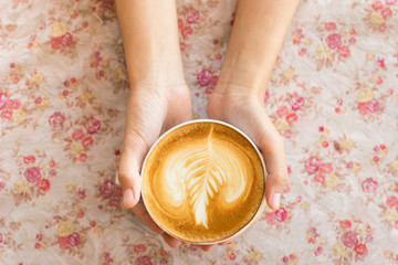 Vintage woman hands holding latte art coffee mug on flower vinta