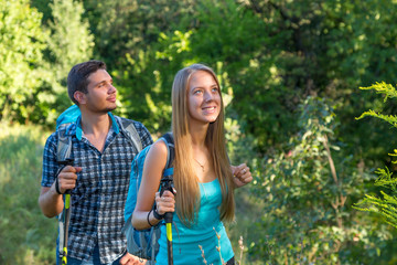 Obraz premium Excited Travelers Young Man and Woman Traveling Outdoor Expressing Fun and Pleasure with Backpacks Walking Poles Sticks and Casual Sporty Style Clothing