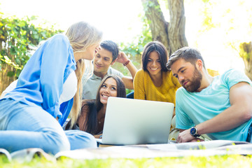 Friends using laptop together outdoors