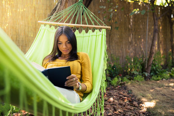 Woman lying on hammok and reading book