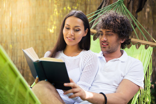 Smiling couple reading book together outdoors