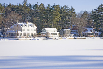 Fototapeta na wymiar Houses on frozen pond with snow, Stow, Ma., New England, USA