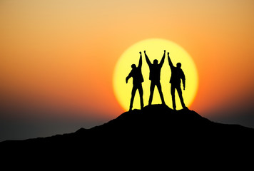 Silhouettes of team on mountain peak. Sport and active life concept.