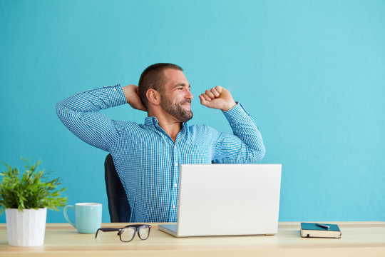 Man working at desk in office stretching his back at desk