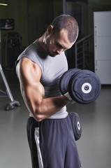 Fototapeta na wymiar Handsome Muscular Male Model Doing Biceps Exercise with Dumbbell