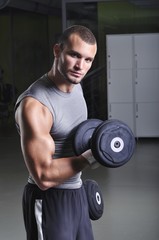 Fototapeta na wymiar Handsome Muscular Male Model Doing Biceps Exercise with Dumbbell