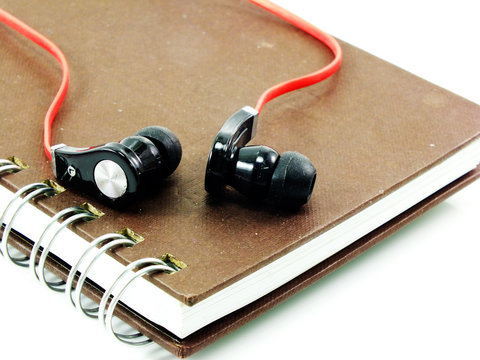 earphones andnote book on white bakground