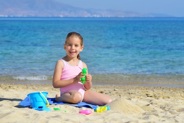 Adorable toddler girl playing with her toys at the beach