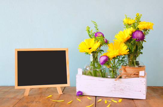 summer bouquet of flowers and wooden blackboard on the wooden table

