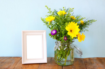 summer bouquet of flowers next to blank vintage photography frame