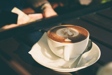 Cup of cappuccino with cinnamon on a wooden table in a cafe