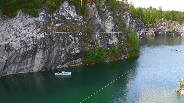 Ropes course, over water. Zip-line. Flying Fox. Activities. Active tourism and travel. Unique natural place. Marble canyon. Sea cliffs. Mountain Park Ruskeala, Karelia. The people riding on the ropes.