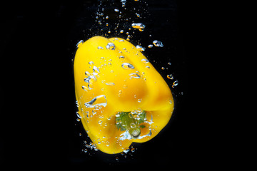 Fototapeta na wymiar Fresh Yellow Bell Pepper Splash in Water on Black Background.