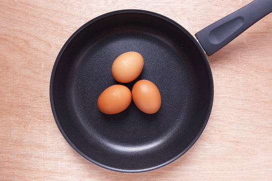 Eggs in Teflon Frying Pan on Wooden Background.