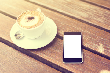 Cup of cappuccino and blank cell phone, mock up