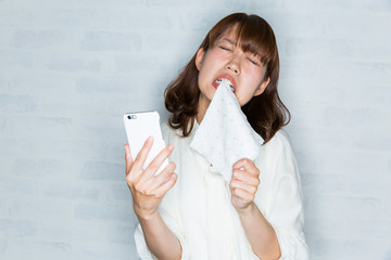 スマートフォン　/ 悔しがる女性