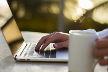 Fototapeta premium Man holding coffee mug and using laptop outdoor