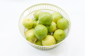 fresh limes in plastic basket on white