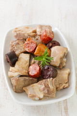 pork, beef, sausages on white plate on white wooden background