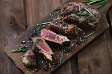 Medium rare grilled ribeye beef steak on a rustic chopping board