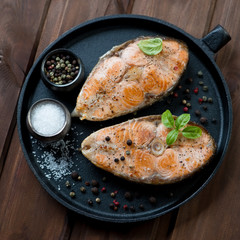 Roasted salmon steaks in a frying pan, above view, closeup
