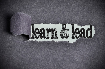 learn and lead word under torn black sugar paper