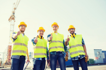 group of smiling builders with tablet pc outdoors