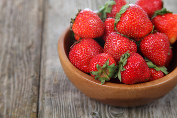Ripe strawberries in a brown bowl