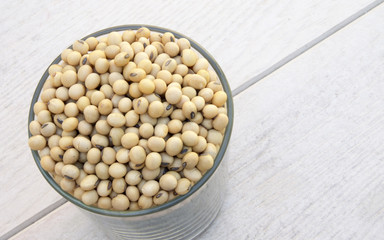 glass of soy beans with white wood background
