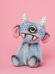 Cute stuffed animal one eyed blue monster toy on a pink background