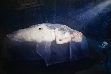 Sleeping Beauty. Beautiful lifeless bride in white dress lying o