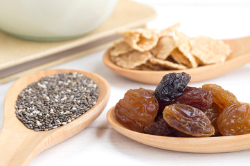 Set of raisins, whole wheat grain flakes and chia seeds in woode