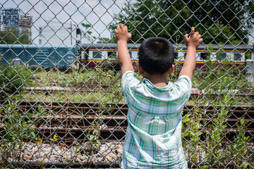asian little boy sad hand hold jail at Railroad,railway station