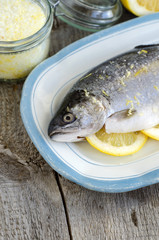 Raw trout stuffed with lemon slices and seasoned with aroma sea salt with lemon peel