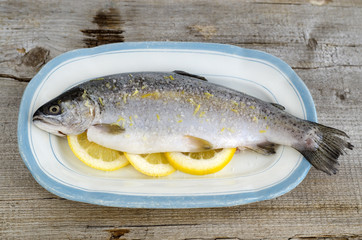 Raw trout stuffed with lemon slices and seasoned with aroma sea salt with lemon peel