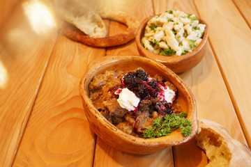 Goulash in ceramic pot/Delicious goulash served with fresh bread and portion of gnocchi