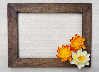 Wooden picture frame and flowers on canvas background 