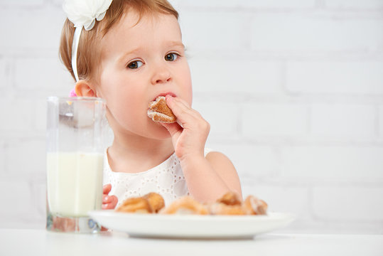 happy child  girl eats cookies and milk