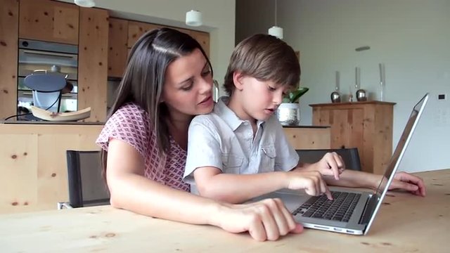 Mother with son doing homework with computer
